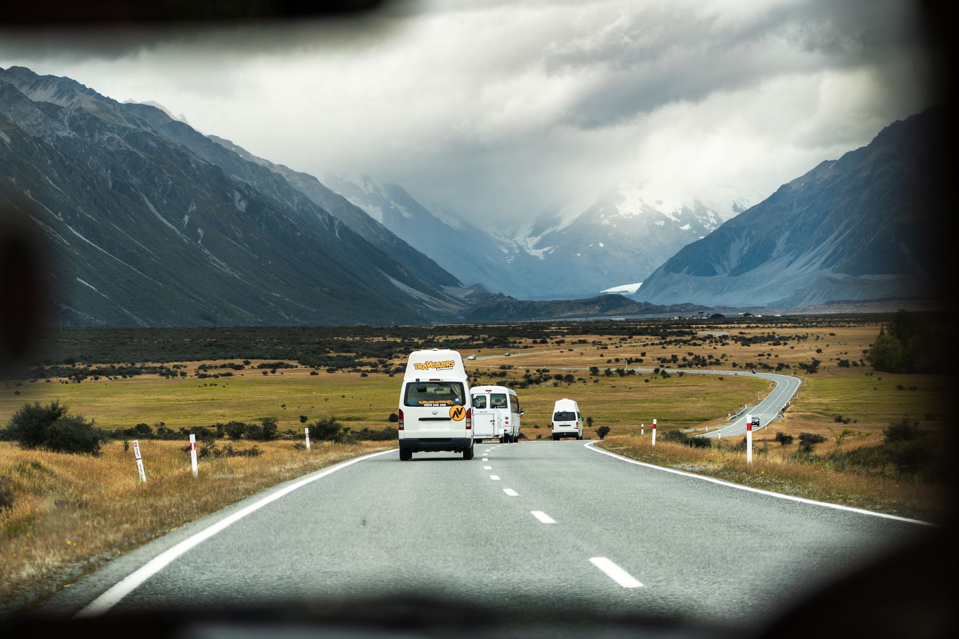 Campervan driving through scenic mountain pass in New Zealand
