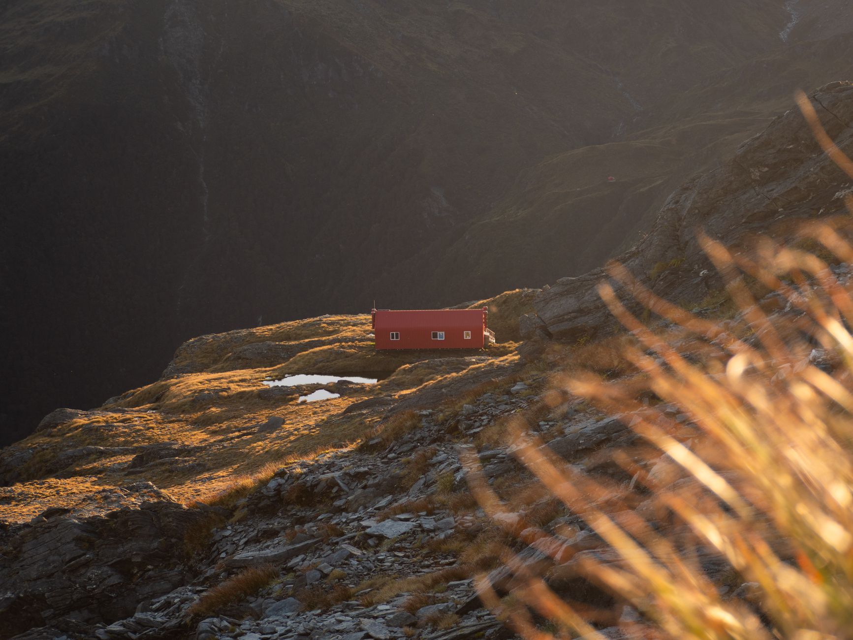 Alpine hut in New Zealand mountains at sunset